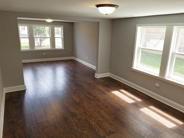 unfurnished room with dark hardwood / wood-style flooring and a healthy amount of sunlight