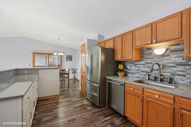 kitchen with appliances with stainless steel finishes, decorative light fixtures, decorative backsplash, sink, and vaulted ceiling