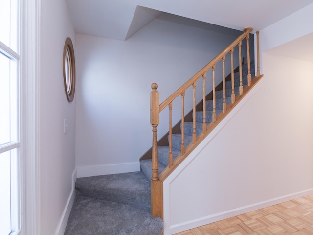 stairway featuring parquet flooring