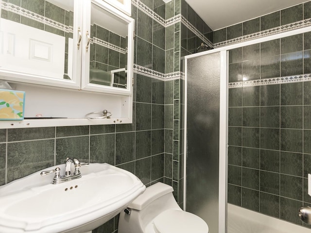 bathroom featuring sink, tile walls, a shower with shower door, and toilet