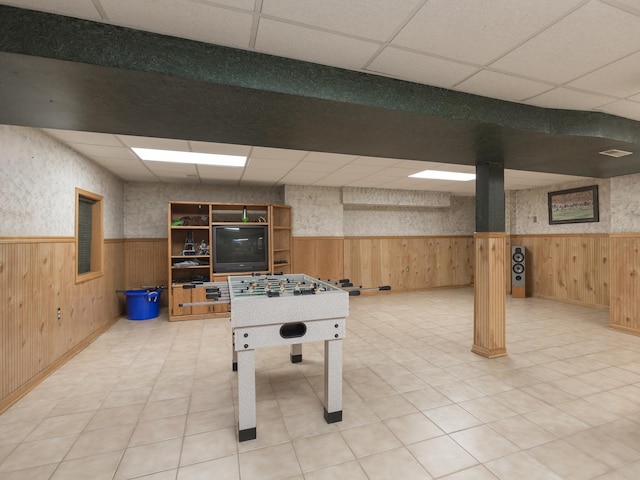 playroom featuring wood walls and a paneled ceiling