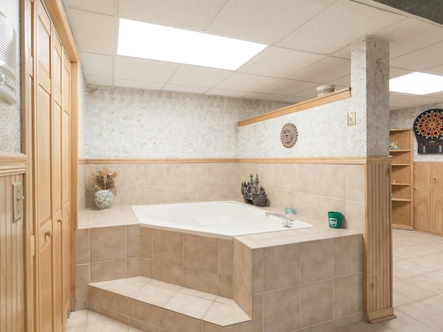 bathroom featuring a drop ceiling, a relaxing tiled tub, and tile patterned floors