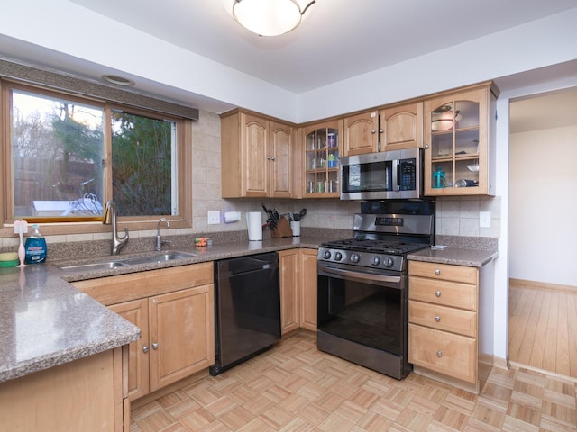 kitchen with stainless steel appliances, sink, light parquet flooring, backsplash, and dark stone counters