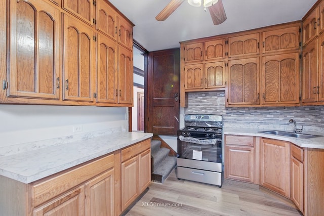 kitchen featuring tasteful backsplash, stainless steel gas stove, light countertops, ceiling fan, and a sink