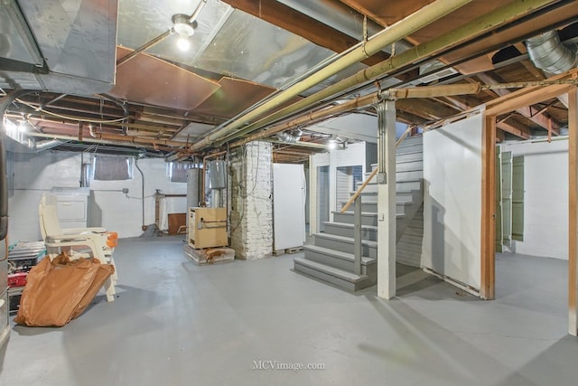 unfinished basement featuring stairs, freestanding refrigerator, and washer / clothes dryer