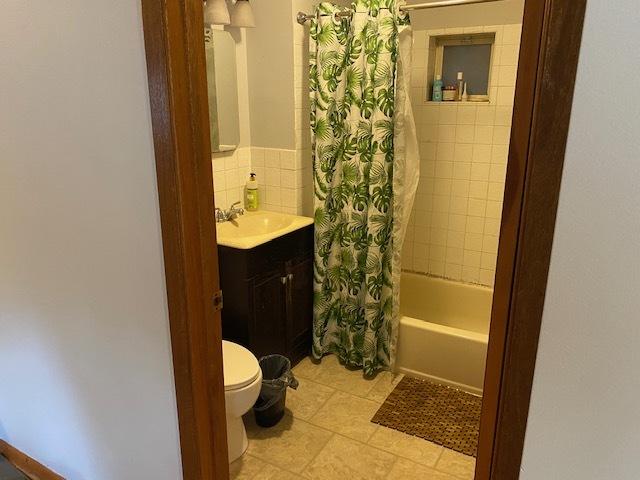 full bathroom featuring toilet, vanity, decorative backsplash, and shower / bath combo with shower curtain