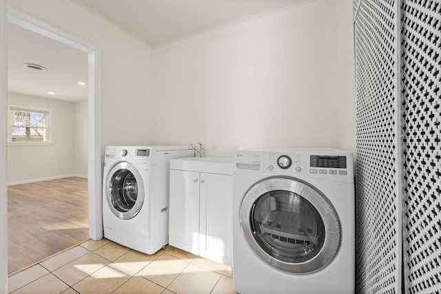 laundry room with washing machine and clothes dryer, ornamental molding, and light tile patterned floors