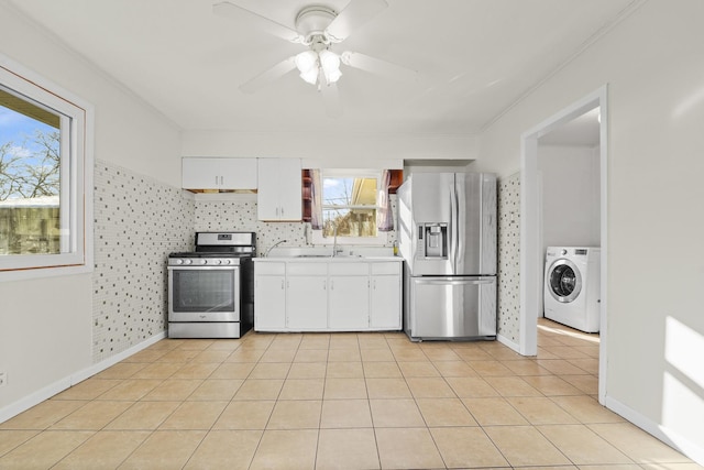 kitchen with appliances with stainless steel finishes, white cabinets, washer / clothes dryer, and light tile patterned flooring