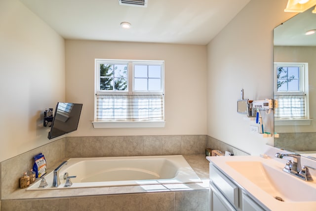 bathroom featuring vanity and a relaxing tiled tub