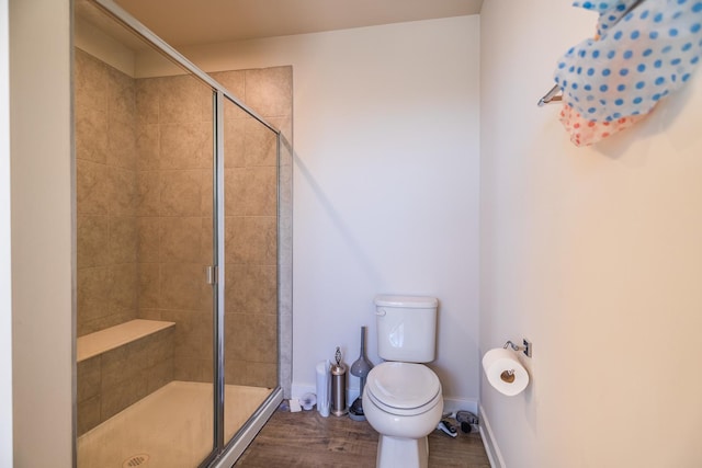 bathroom with toilet, a shower with door, and hardwood / wood-style floors