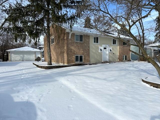 snow covered rear of property with a garage and an outdoor structure