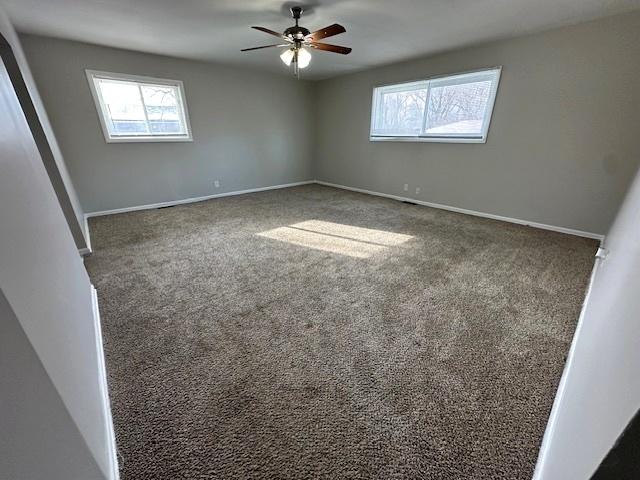 carpeted spare room featuring ceiling fan