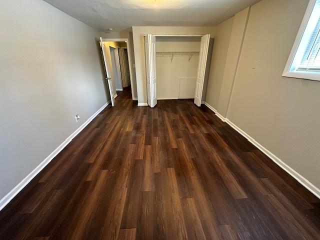 unfurnished bedroom featuring dark wood-type flooring and a closet