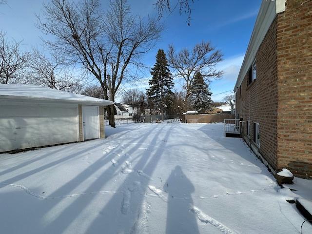 snowy yard featuring a garage and an outdoor structure