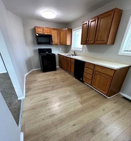 kitchen with sink, light wood-type flooring, and black appliances