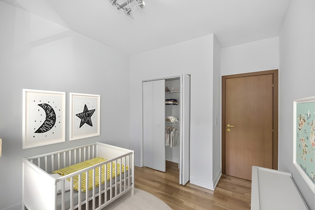 bedroom with a closet, a crib, and light hardwood / wood-style flooring