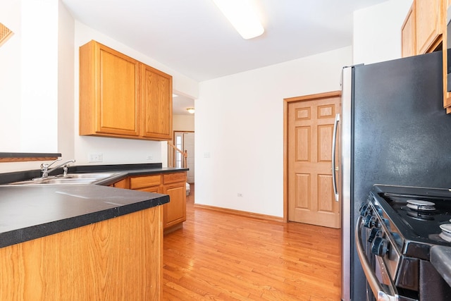 kitchen with sink, light hardwood / wood-style floors, and stove