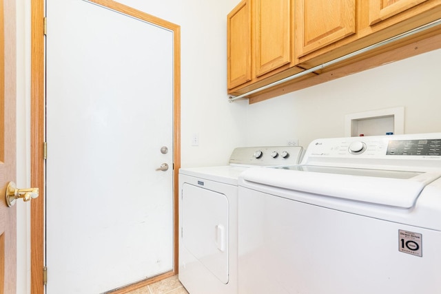 clothes washing area featuring cabinets, washer and clothes dryer, and light tile patterned flooring