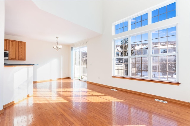 unfurnished living room with a notable chandelier and light hardwood / wood-style floors