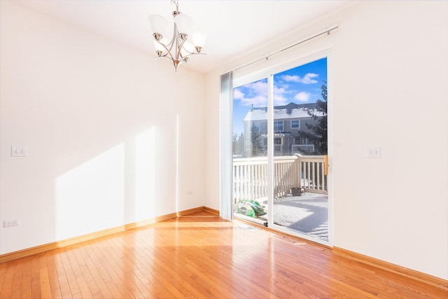 empty room with a notable chandelier and hardwood / wood-style floors