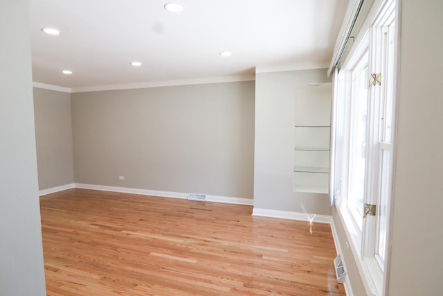 empty room featuring light wood-type flooring and crown molding