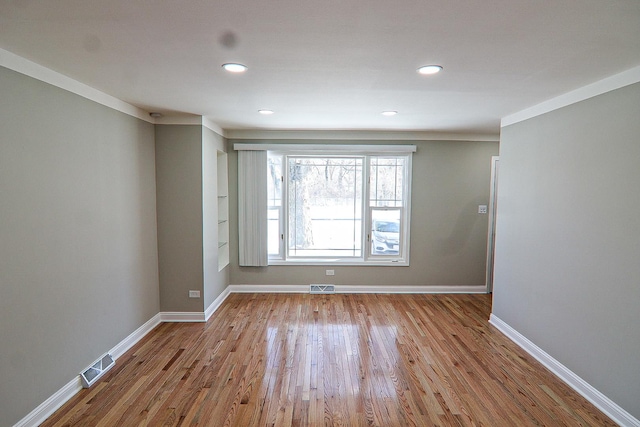 spare room featuring light wood-type flooring and crown molding