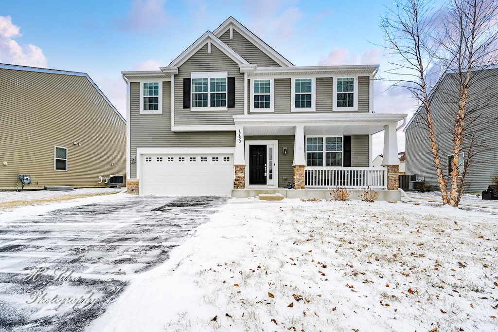 craftsman-style home featuring a garage, covered porch, and central air condition unit