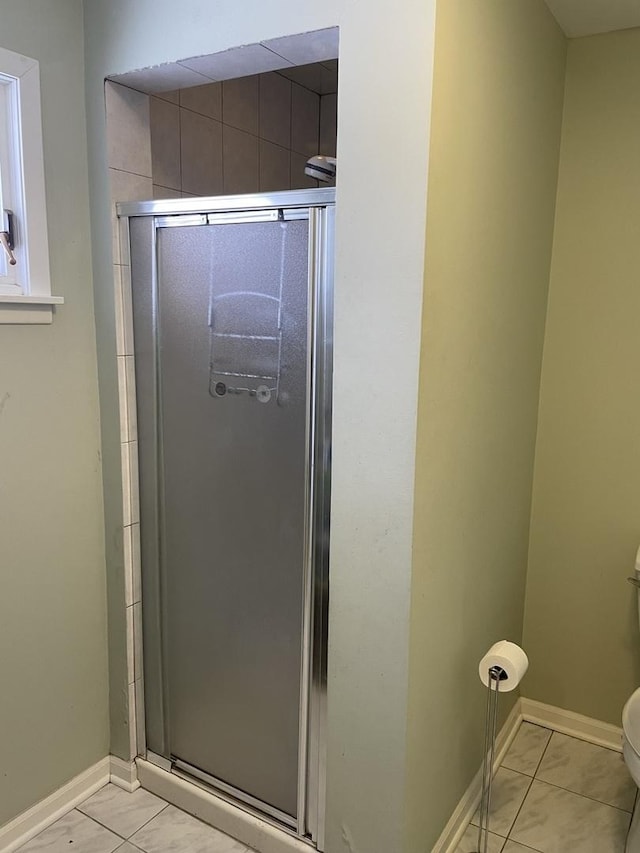 bathroom featuring tile patterned floors, toilet, and a shower with shower door