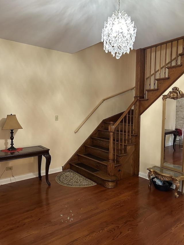 staircase with hardwood / wood-style floors and a notable chandelier