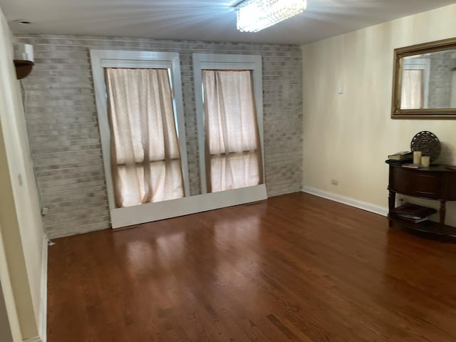 unfurnished room featuring dark hardwood / wood-style floors and brick wall