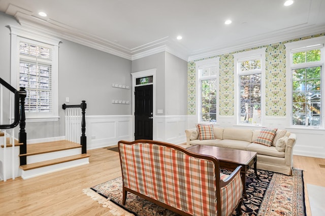 living room with light hardwood / wood-style flooring, ornamental molding, and a healthy amount of sunlight