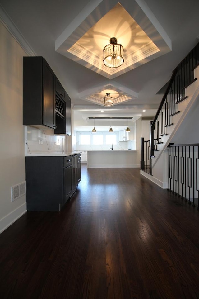 kitchen with dark wood-type flooring, pendant lighting, backsplash, and a raised ceiling