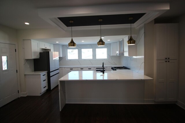 kitchen with refrigerator, pendant lighting, kitchen peninsula, sink, and white cabinets