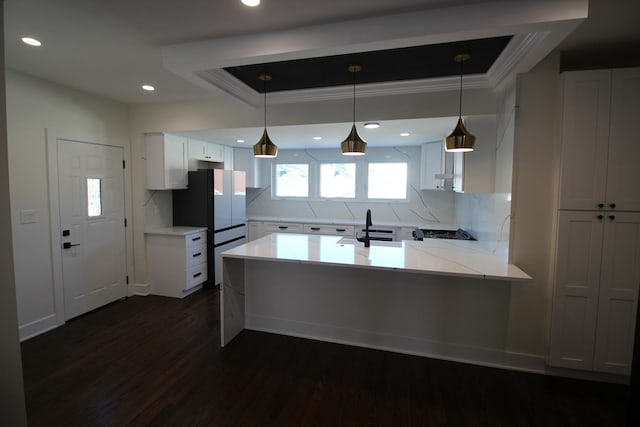 kitchen featuring white cabinets, decorative backsplash, hanging light fixtures, dark hardwood / wood-style floors, and kitchen peninsula