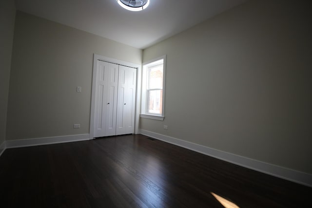 unfurnished bedroom featuring dark wood-type flooring and a closet