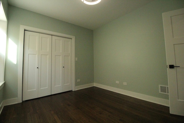 unfurnished bedroom with a closet and dark hardwood / wood-style floors