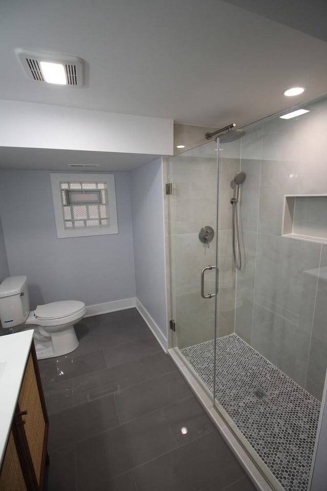 bathroom with toilet, tile patterned flooring, a shower with door, and vanity