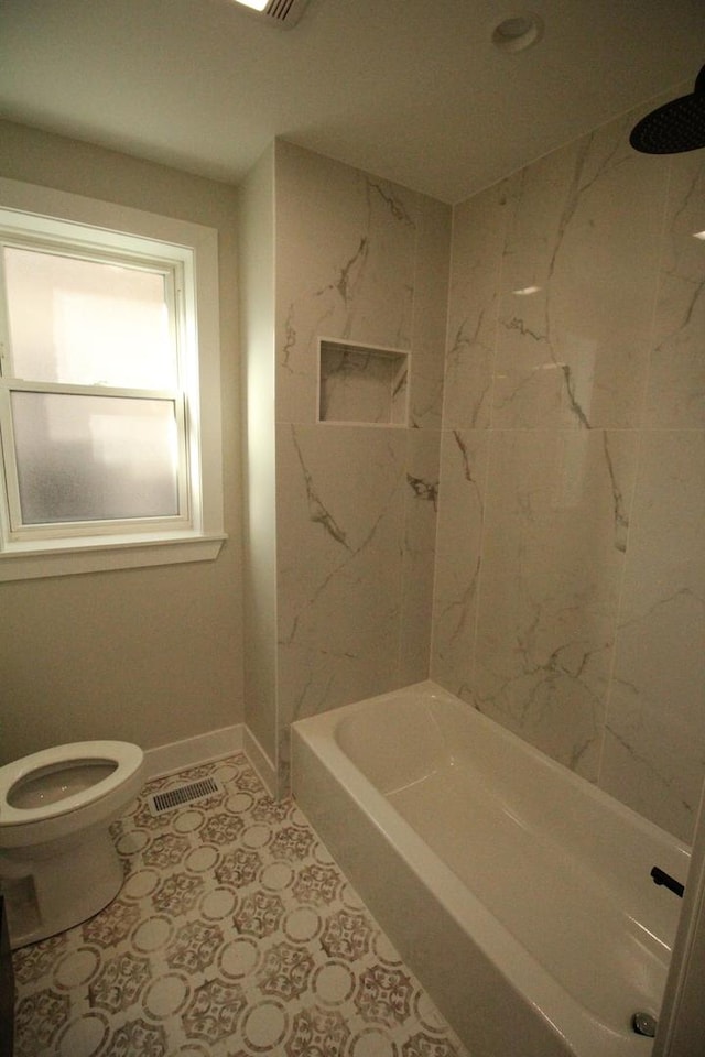 bathroom with toilet and tiled shower / bath combo