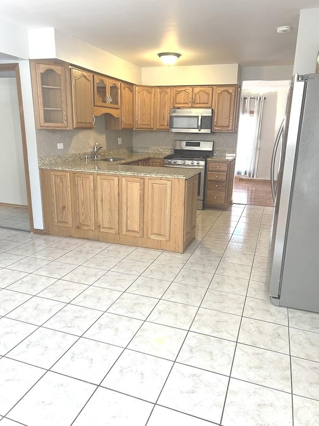 kitchen featuring sink, light tile patterned floors, backsplash, light stone countertops, and appliances with stainless steel finishes