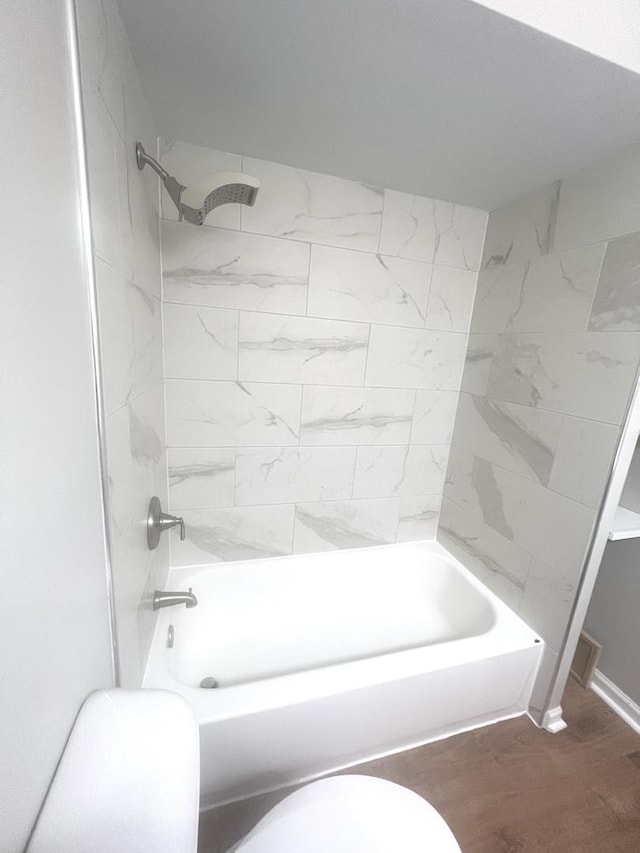 bathroom featuring toilet, hardwood / wood-style floors, and tub / shower combination