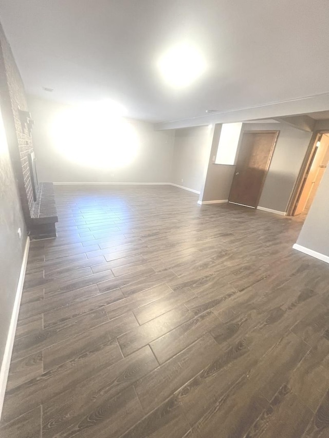 empty room featuring dark hardwood / wood-style flooring and a brick fireplace