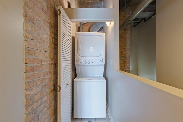 2545 S Dearborn St Unit 508, Chicago, IL 60616 - clothes washing area with stacked washing machine and dryer, baseboards, and brick wall