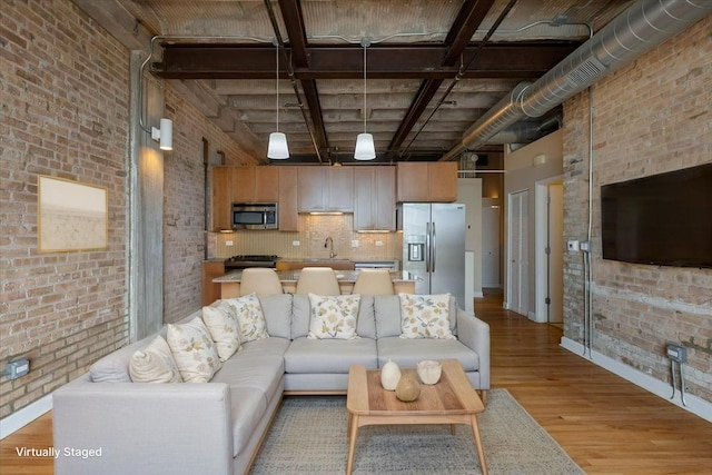 2545 S Dearborn St Unit 508, Chicago, IL 60616 - living room featuring brick wall, light wood finished floors, a high ceiling, and baseboards