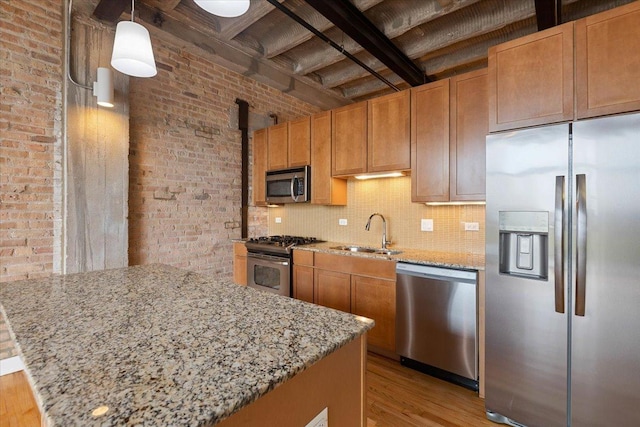2545 S Dearborn St Unit 508, Chicago, IL 60616 - kitchen featuring appliances with stainless steel finishes, a sink, brick wall, light wood-style floors, and light stone countertops