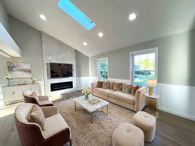 living room with a skylight, high vaulted ceiling, a fireplace, and wood-type flooring