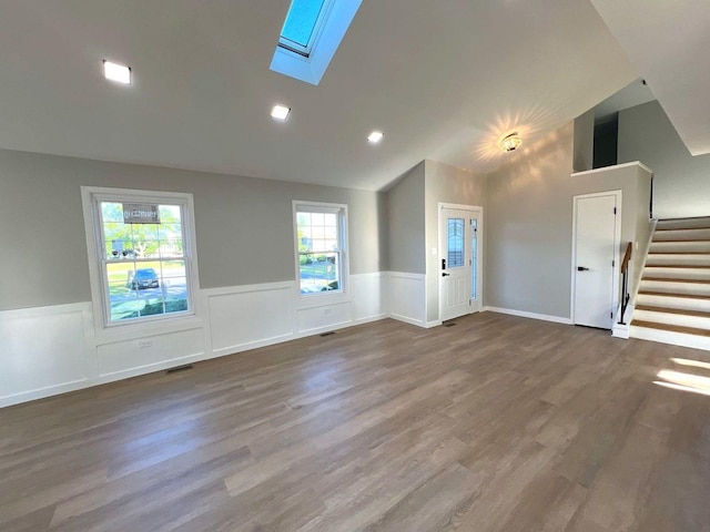 unfurnished living room featuring lofted ceiling with skylight and hardwood / wood-style flooring