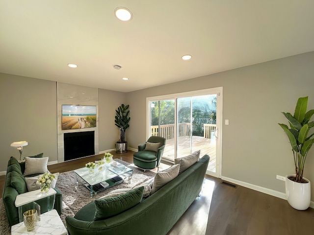 living room featuring a tiled fireplace and dark hardwood / wood-style floors