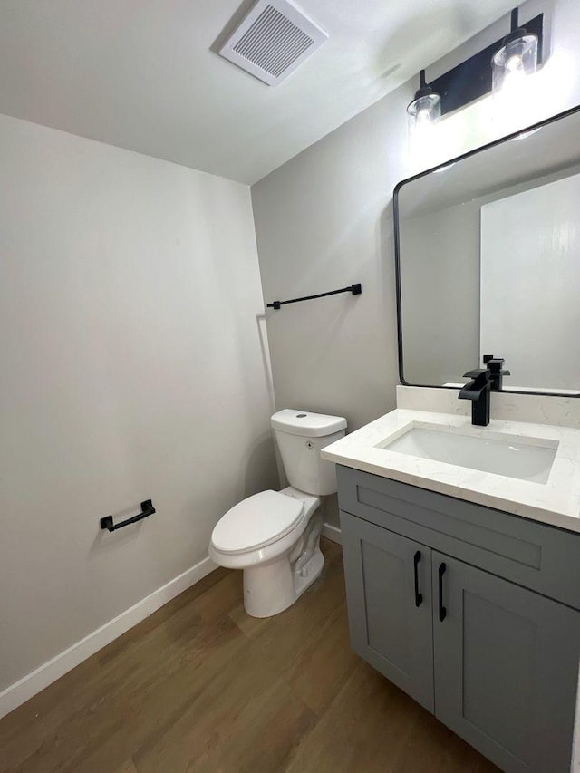 bathroom with toilet, vanity, and hardwood / wood-style floors