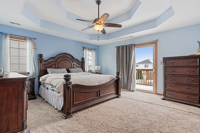 bedroom featuring ceiling fan, access to exterior, light carpet, and a raised ceiling