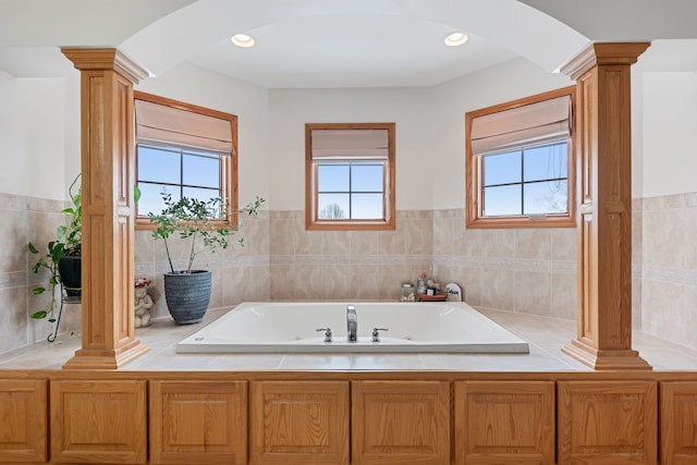 bathroom with a tub, a healthy amount of sunlight, and ornate columns